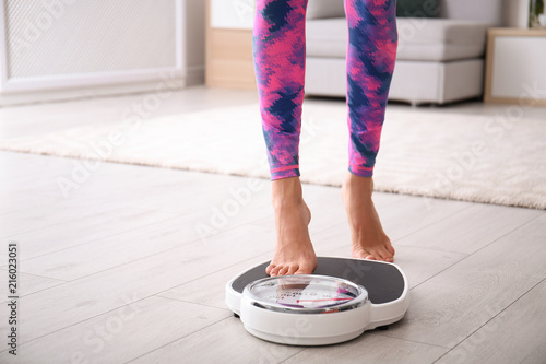 Woman measuring her weight using scales on floor
