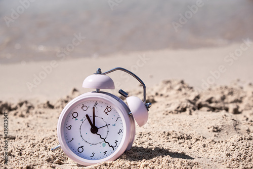 Vacation time. Alarm clock on the sand.