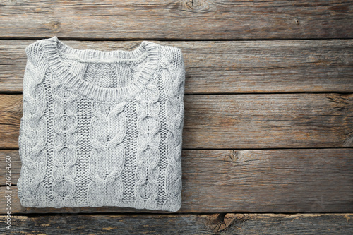 Knitted grey sweater on wooden table