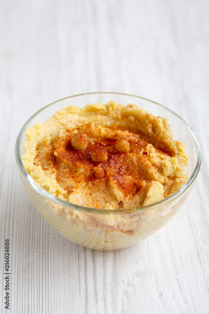Bowl of Hummus with roasted chickpeas, paprika, olive oil on a white wooden table, side view. Closeup. Bowl of Hummus with roasted chickpeas, paprika, olive oil on a white wooden table, side view. Closeup.