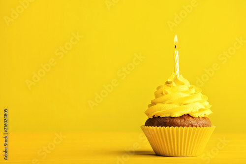 Tasty cupcake with candle on yellow background