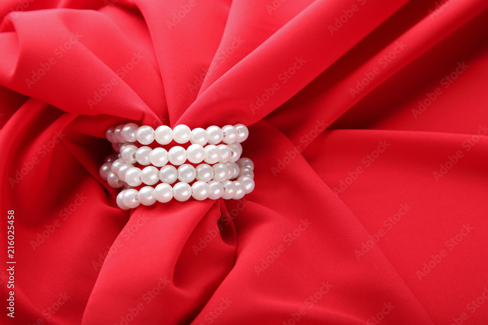 Pearl necklace on red satin fabric Pearl necklace on red satin fabric