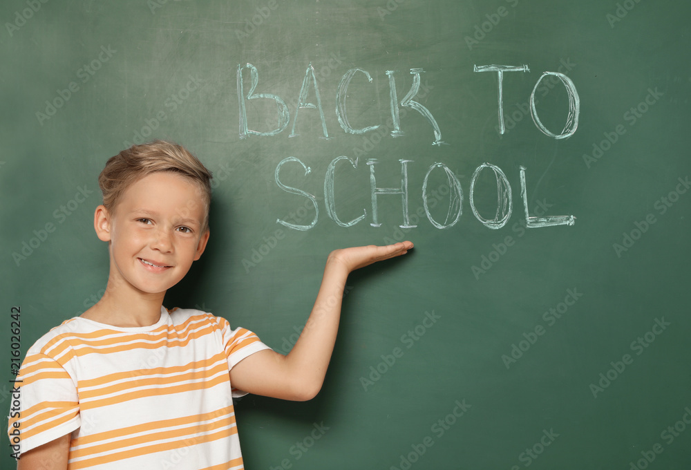 Little child near chalkboard with text BACK TO SCHOOL Little child near chalkboard with text BACK TO SCHOOL
