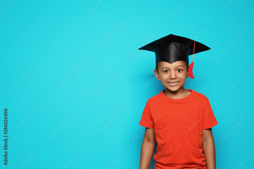 Little African-American school child with graduate cap on color background Little African-American school child with graduate cap on color background