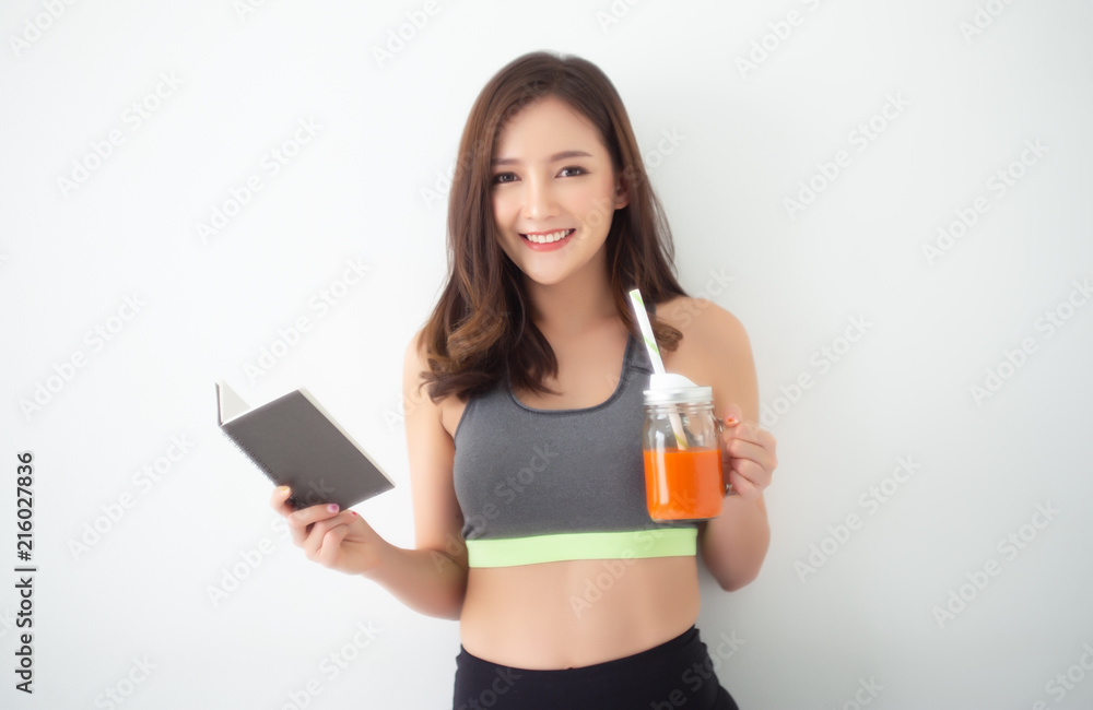 Φωτογραφία Happy young Asian woman drinking Fresh Raw Detox Vegetable Juice and reading a book in room looking at camera