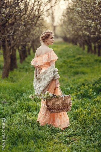 Beautiful young girl in an old dress in a pear-blossoming garden.