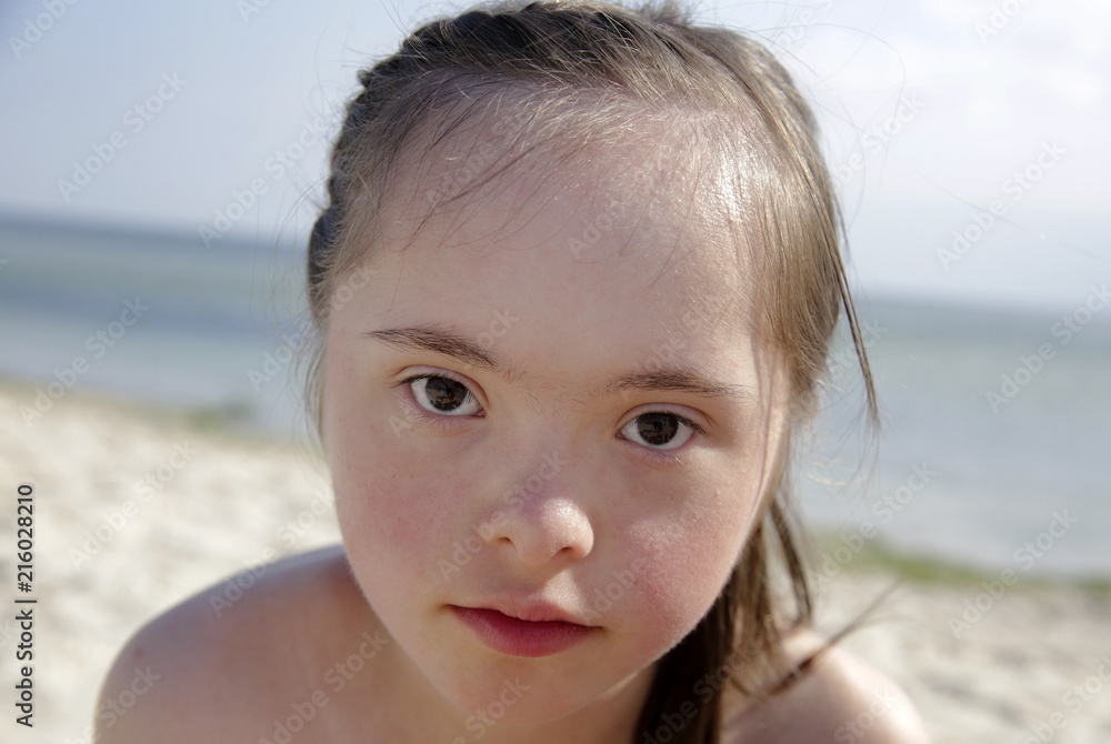 Portrait of down syndrome girl smiling on background of the sea