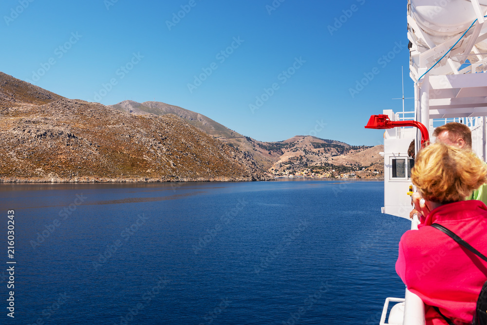 Fototapeta premium A cruise ship with tourists on board approaches the island of Symi. Dodecanese, Greece