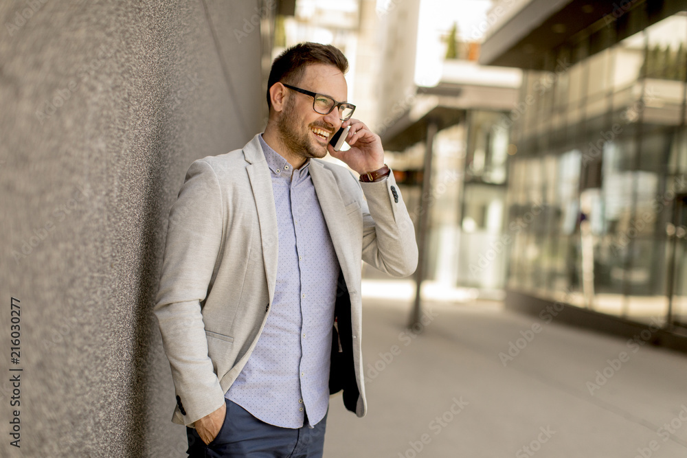 Young businessman with mobile phone by the grey wall Young businessman with mobile phone by the grey wall