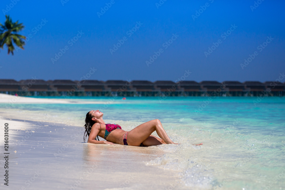 Schöne junge Frau liegt am Strand der Malediven