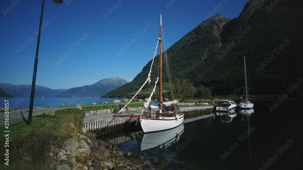 Sailboat at a harbor with a view at the fjord in Norway. Hardangerfjord near Kinsarvik filmed in summer on a bright sunny day. Sailboat at a harbor with a view at the fjord in Norway. Hardangerfjord near Kinsarvik filmed in summer on a bright sunny day.