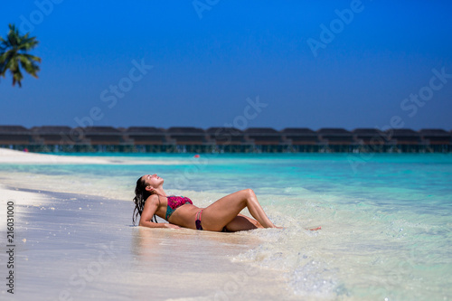 Schöne junge Frau liegt am Strand der Malediven