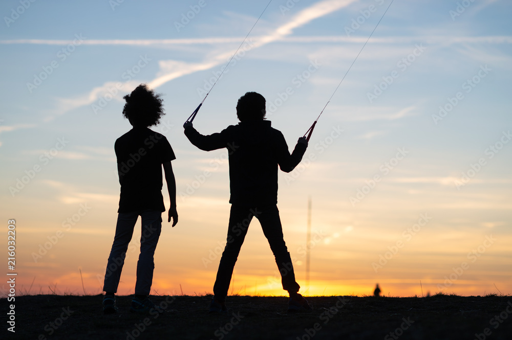 Children play with stunt kite at sunset