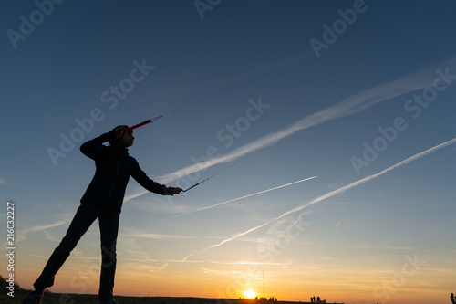 Kid towing stunt kite against eveing sky