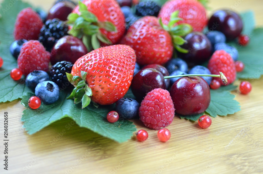 Detail of fresh summer fruit and berries on a bamboo board. Strawberries, raspberries, cherries, blackberries, blueberries and red currants on fresh green leaves with copy space.
Detail of fresh summer fruit and berries on a bamboo board. Strawberries, raspberries, cherries, blackberries, blueberries and red currants on fresh green leaves with copy space.