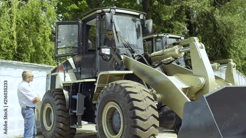 Manager demonstrates buyer how work the tractor