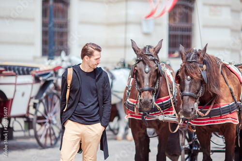 Photography Tourist man enjoying a stroll through Vienna and looking at the two horses in th