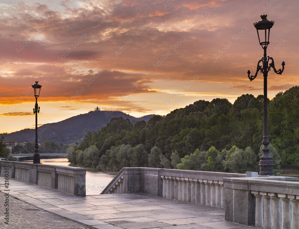 Two street lighters on the embankment in front of river in sunset time in Turin in Italy
