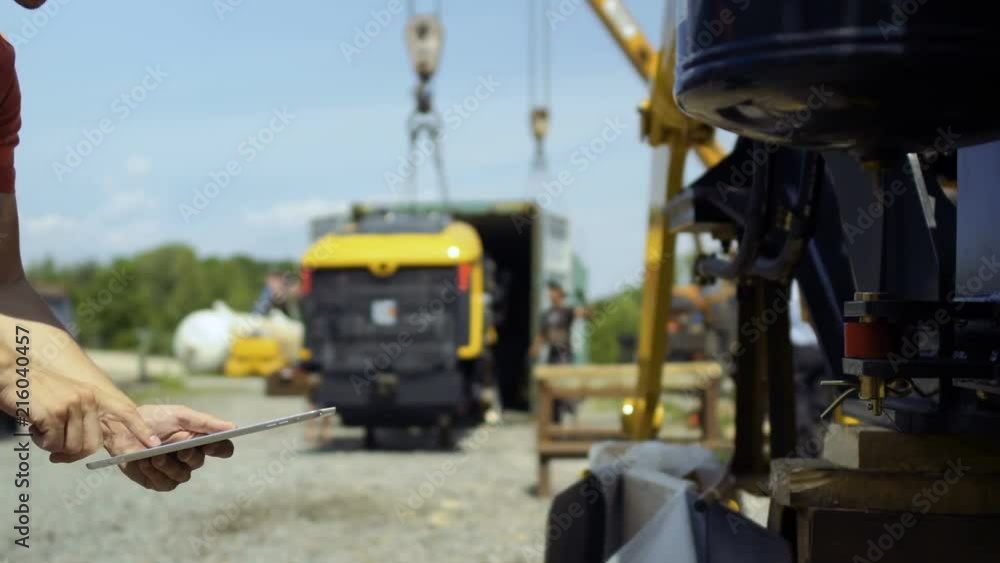 Engineer using tablet at blurred background of cargo loading inside container Engineer using tablet at blurred background of cargo loading inside container
