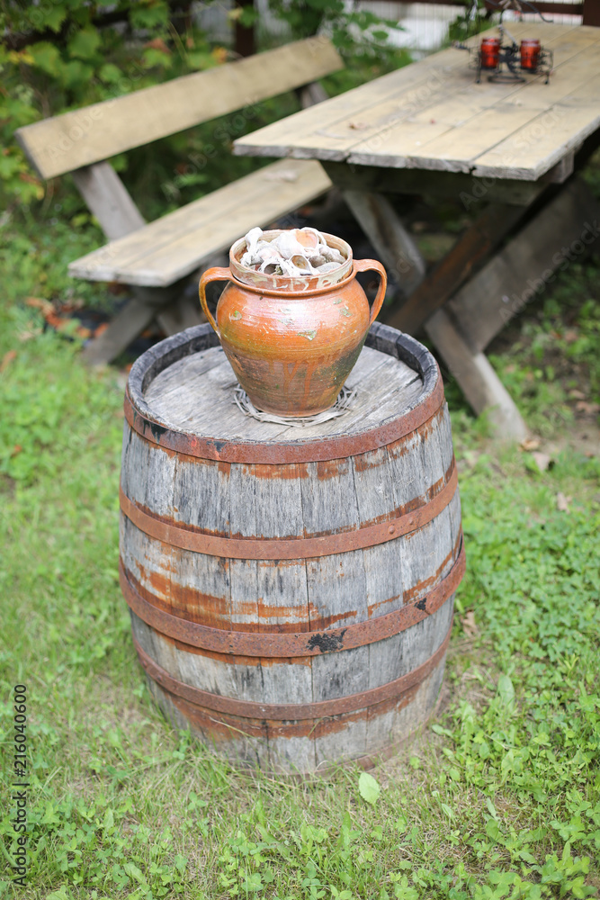 Obraz premium Clay pot filled with empty sea snails shells on a rusty old barrel