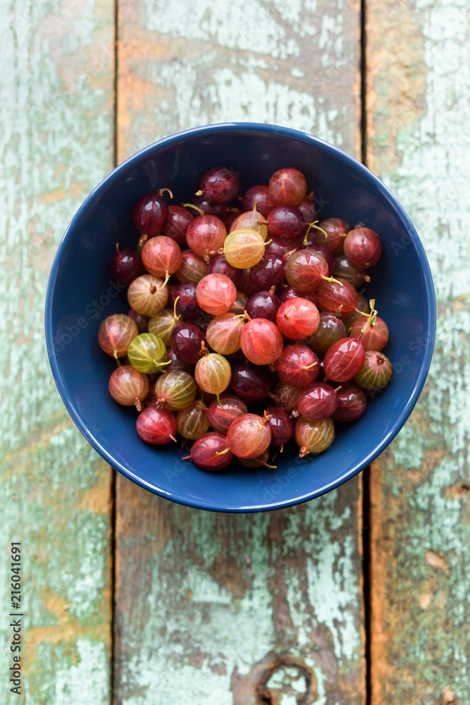 Organic berries. Pink gooseberries in blue bowl on shabby blue wooden background copyspace Organic berries. Pink gooseberries in blue bowl on shabby blue wooden background copyspace