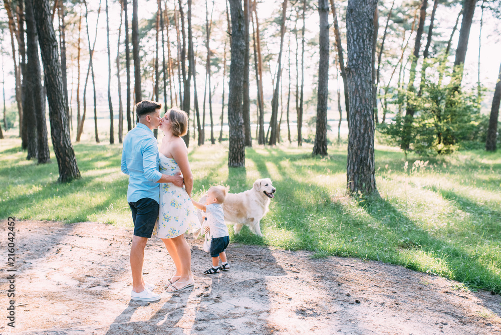 Fototapeta premium A cute family - mom, dad and son spend fun time outdoors with their dog