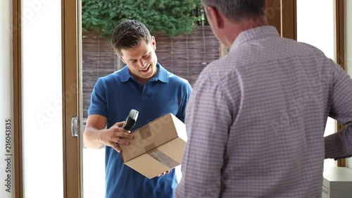 Man At Home Opens Door To Courier Delivering Package 