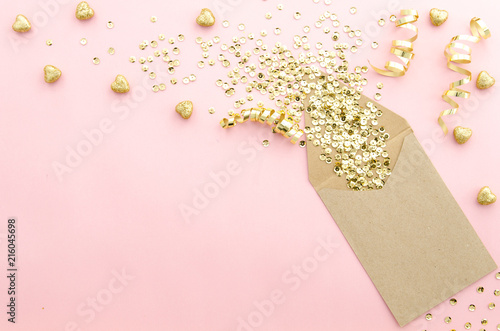 Envelope with gold glitter sequins, confetti and hearts on a gently pink background. Mockup template. View from above photo