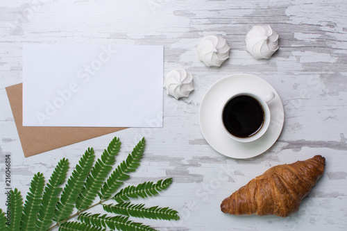 Blank page on rustic wooden background with croasant, coffee, marshmallows. Vintage mockup with text place photo