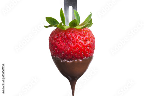 Fondue strawberry soaked in hot black chocolate on a fork isolated on white background