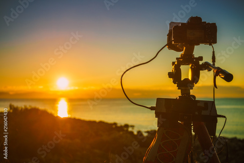 Camera taking picture film of sunrise over sea surface