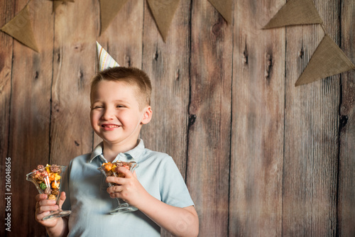 Laughing baby lying on the wooden floor with festive caps and candles on a carnival party. Healthy smiling, Happy childhood concept. photo