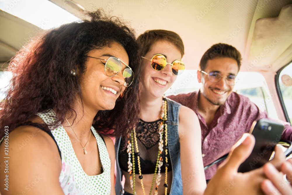 Mixed group of happy young people in a camper van having fun 