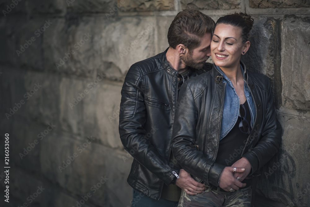 Passionate and cute young couple hugging and kissing in a dark corner of the city street Passionate and cute young couple hugging and kissing in a dark corner of the city street