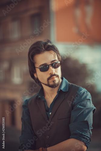 Fashionable elegant and confident young man standing in the city, posing next to a motor bike © Teodor Lazarev