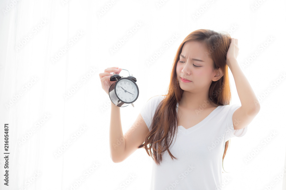 Beautiful young asian woman wake up in morning annoyed alarm clock holding hand, girl standing hurry wake late with appointment with curtain background on bedroom, lifestyle concept. Beautiful young asian woman wake up in morning annoyed alarm clock holding hand, girl standing hurry wake late with appointment with curtain background on bedroom, lifestyle concept.