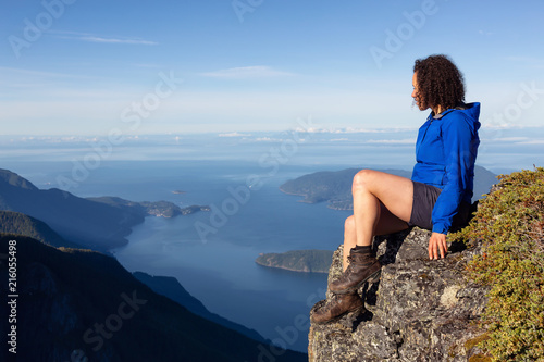Adventurous woman is enjoying the view in the mountains during a sunny summer day. Taken on Mount Brunswick, Lions Bay, North of Vancouver, BC, Canada.