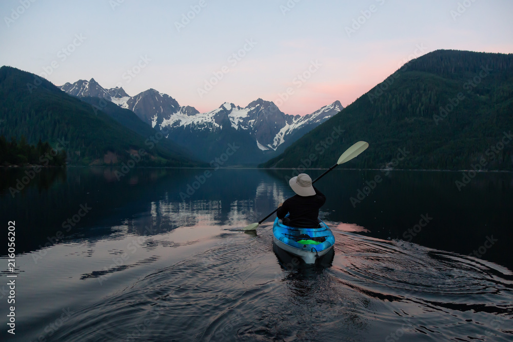 Adventurous man kayaking in the water surrounded by the Beautiful Canadian Mountain Landscape. Taken in Jones Lake, near Hope, East of Vancouver, BC, Canada. Adventurous man kayaking in the water surrounded by the Beautiful Canadian Mountain Landscape. Taken in Jones Lake, near Hope, East of Vancouver, BC, Canada.
