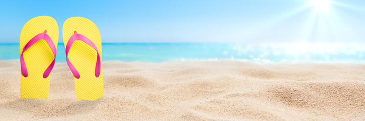 Colorful flip flops on beach against sunny sky