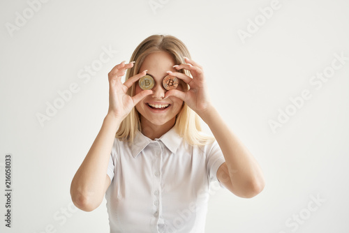 smiling business woman holds bitcoins near the eyes