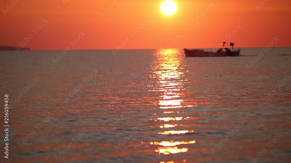 A fishing boat passes by sunrise A fishing boat passes by sunrise