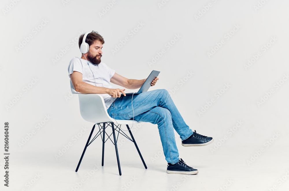 man sitting on a chair in headphones with a laptop man sitting on a chair in headphones with a laptop