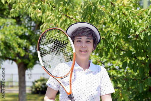 公園でテニスラケットを持ち微笑む女性 © tomoco_sozai