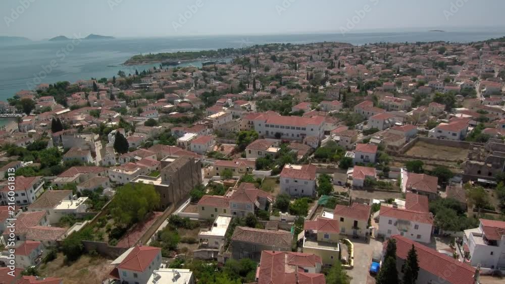 Aerial shot above the island Spetses in Saronic gulf of Greece. View of the city and the port. Slow rotation following the whole island perimeter. Lift off and landing movement.