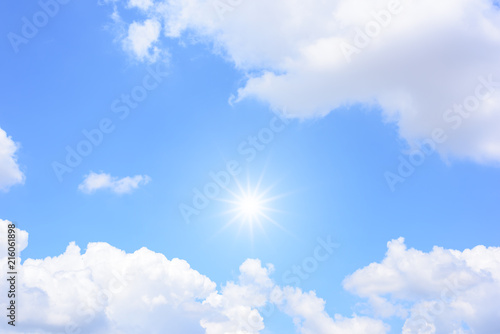 Sun on blue sky with white clouds.