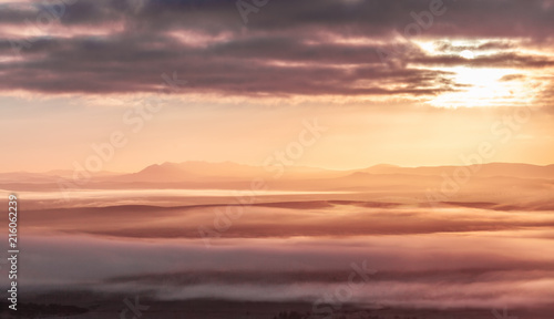 Mountain silhouettes and low morning clouds at sunrise