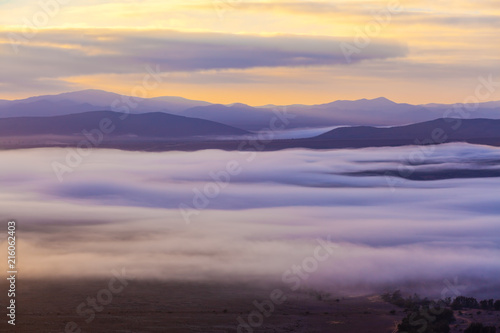 Low clouds covering mountain peaks at sunset