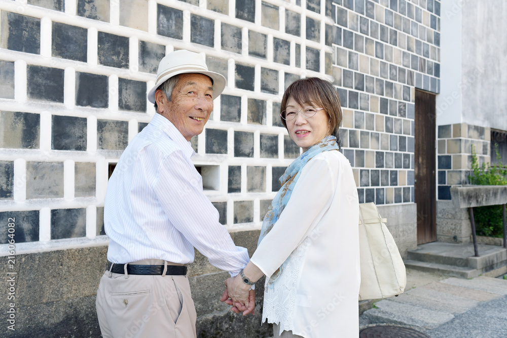 Fototapeta premium 旅先の街角で、笑顔で振り返るシニア夫婦