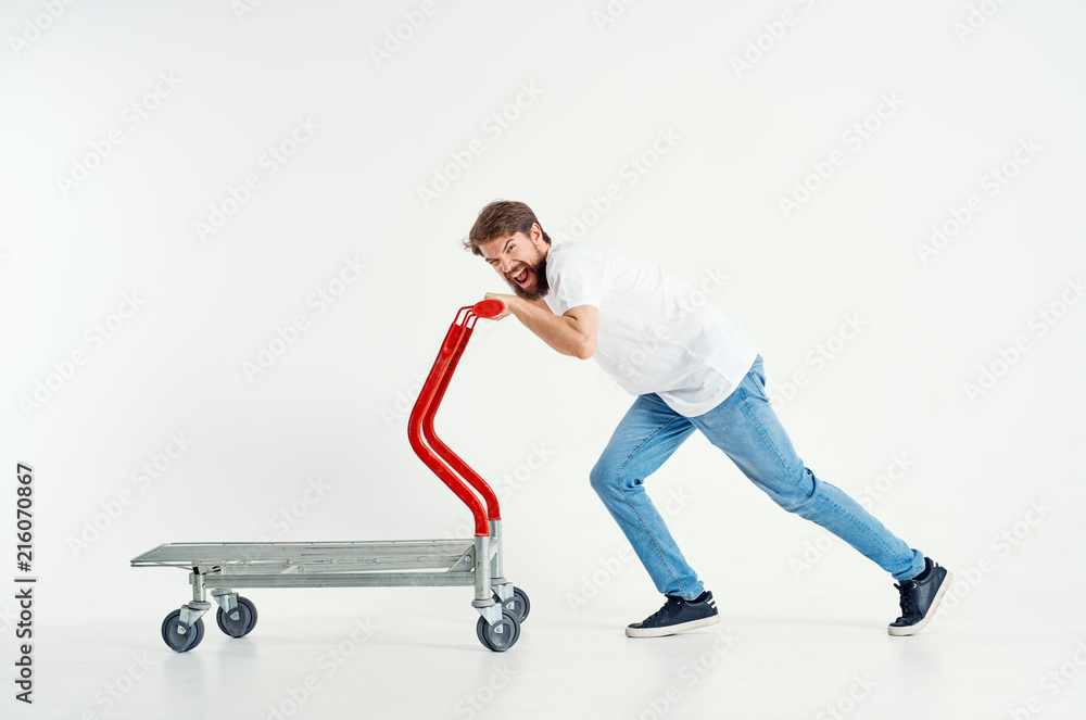cheerful man rolls the cart on an isolated white background cheerful man rolls the cart on an isolated white background