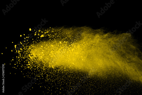 Abstract of yellow powder explosion on black background. Yellow powder splatted isolate. Colored cloud. Colored dust explode. Paint Holi.
